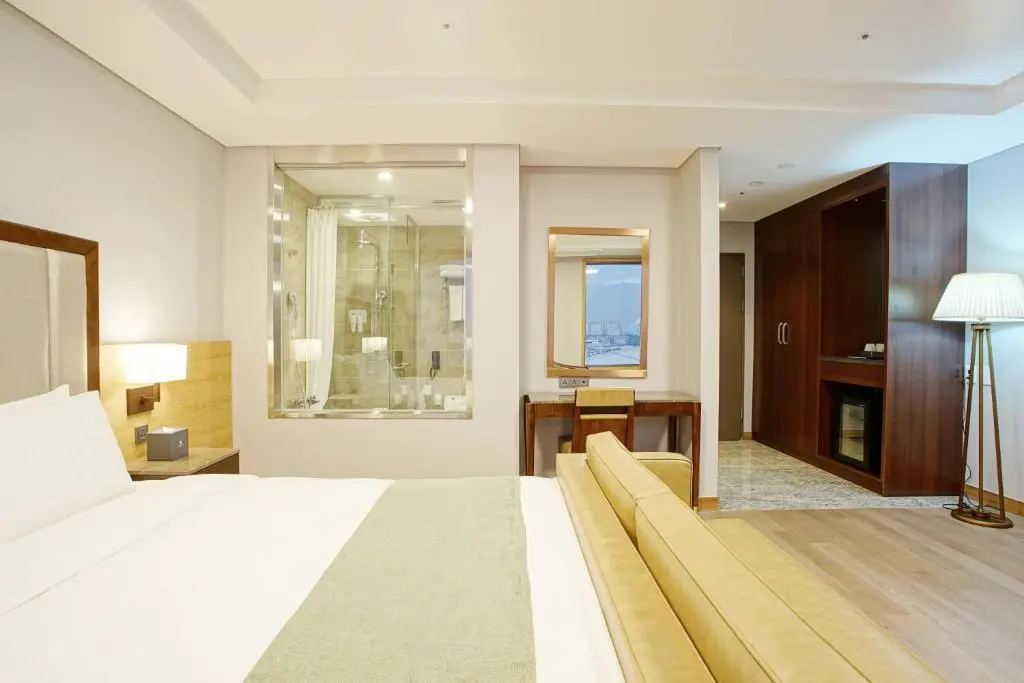 Guestroom with a bed, sofa and glass-walled bathroom